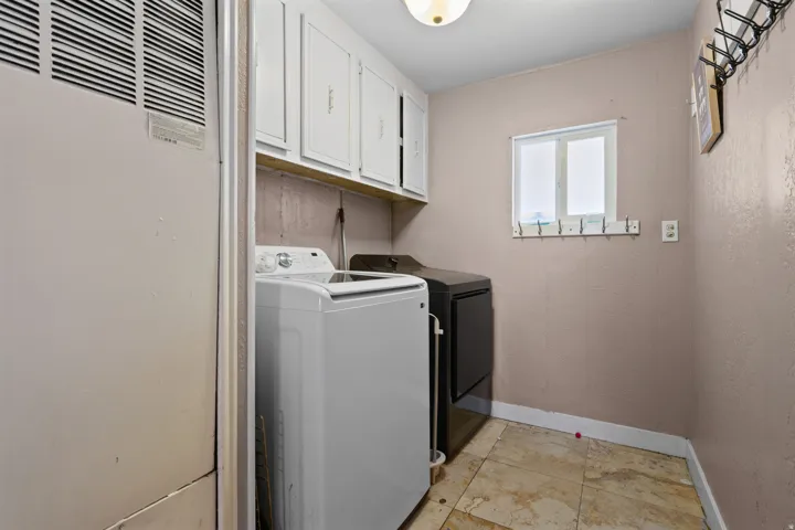 Laundry area featuring a heating unit, cabinet space, independent washer and dryer, and light tile patterned floors