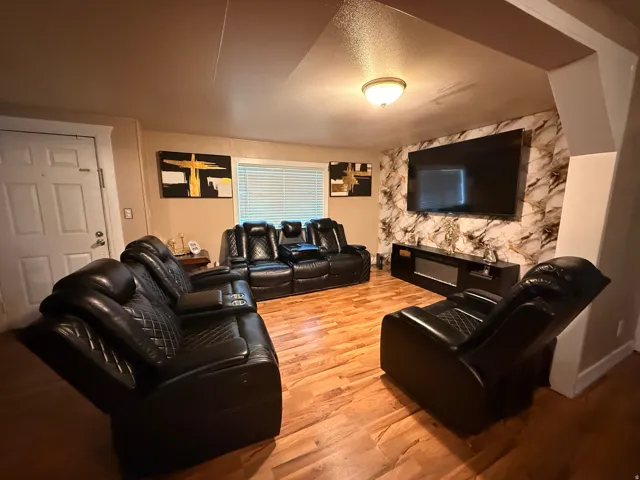Wood-finish flooring, accent wall with a marble-effect finish, recessed ceiling lighting, and a white paneled door