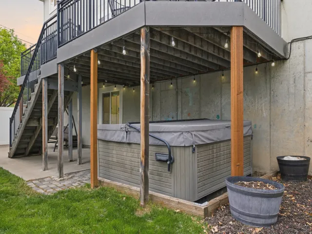 Patio terrace at dusk featuring a patio, a wooden deck, and a hot tub