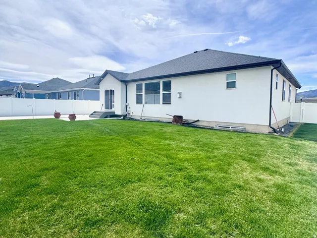 View of property exterior with a fenced backyard, stucco siding, and roof with shingles