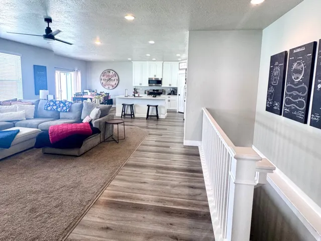 Living area featuring dark wood-style flooring, recessed lighting, a textured ceiling, and a ceiling fan