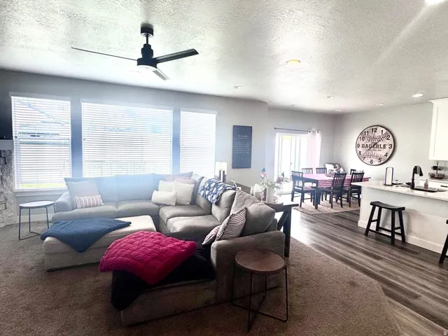 Living area with a textured ceiling, dark wood-style floors, and ceiling fan
