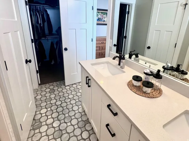 Bathroom featuring double vanity, a walk in closet, and a textured ceiling
