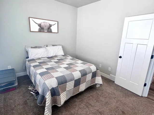 Bedroom with dark carpet and a textured ceiling