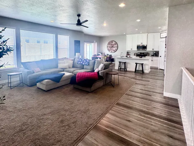Living area with dark wood-type flooring, a textured ceiling, ceiling fan, and recessed lighting