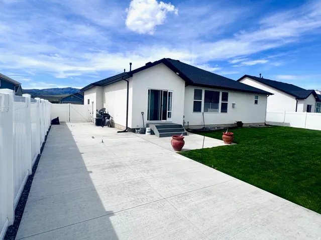 Rear view of house featuring a fenced backyard, a patio area, entry steps, a gate, and stucco siding
