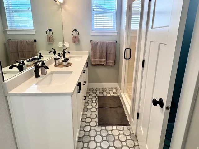 Bathroom featuring double vanity, a stall shower, and a textured ceiling