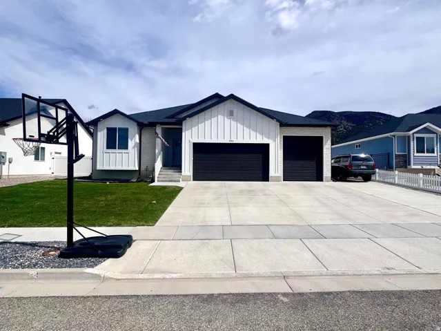 Modern farmhouse with board and batten siding, an attached garage, driveway, and a front yard