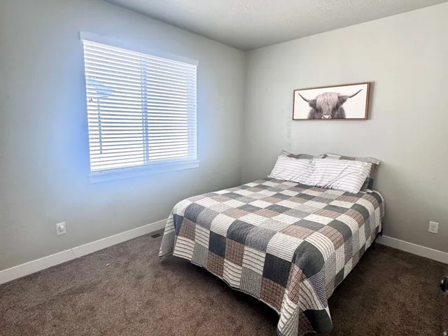 Bedroom with dark carpet and a textured ceiling