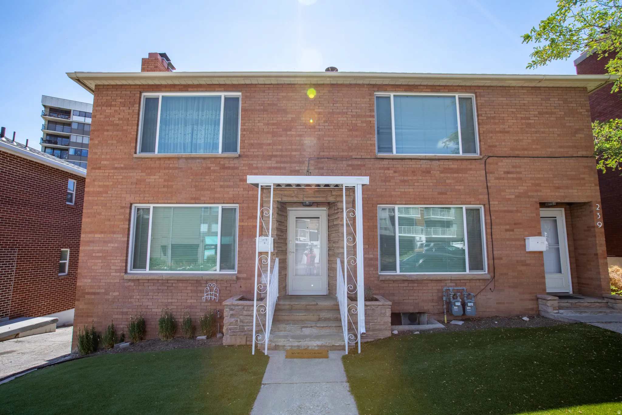 View of front of house with brick siding, a front yard, and a chimney