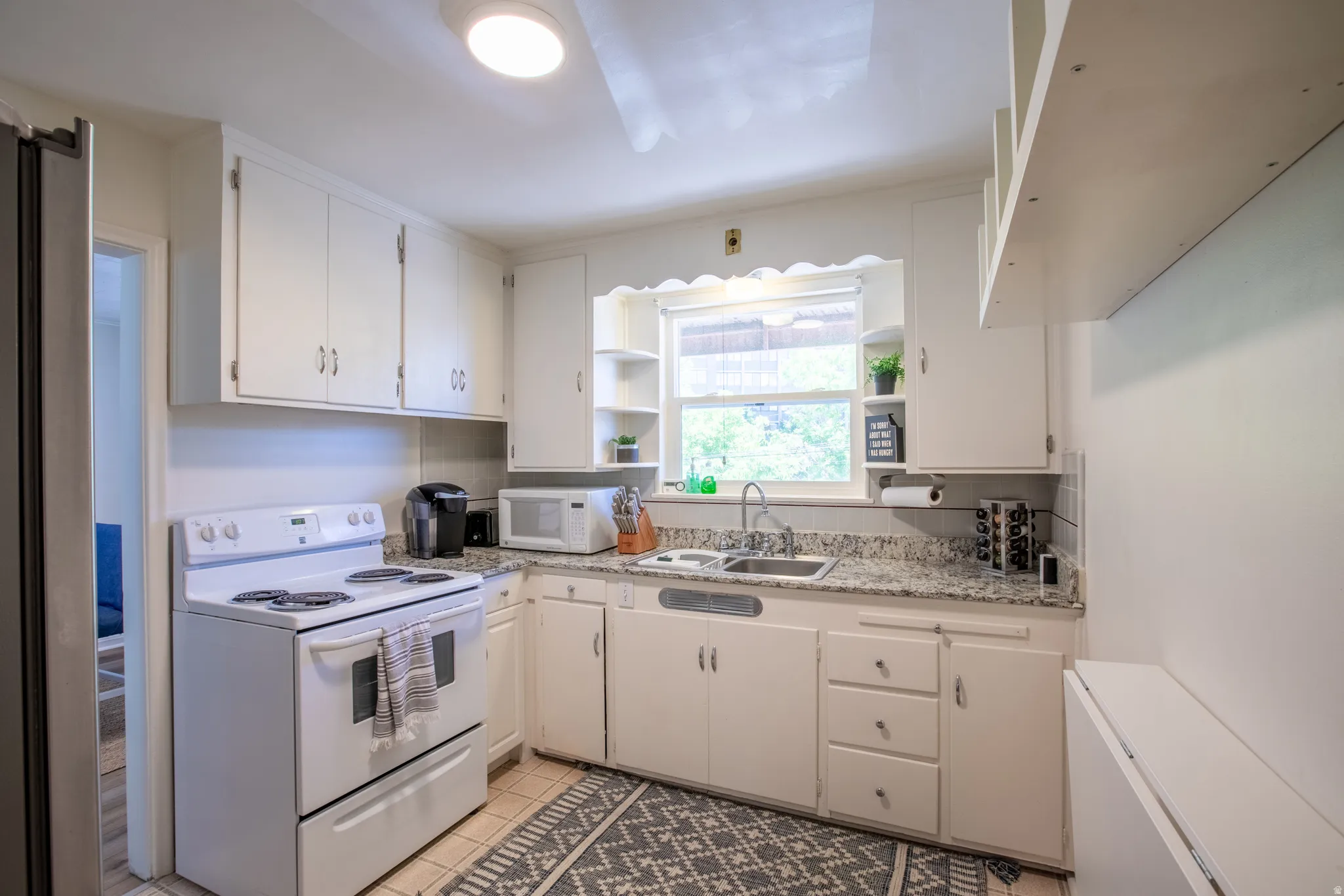 Kitchen featuring white appliances, white cabinetry, range hood, open shelves, and light tile patterned floors