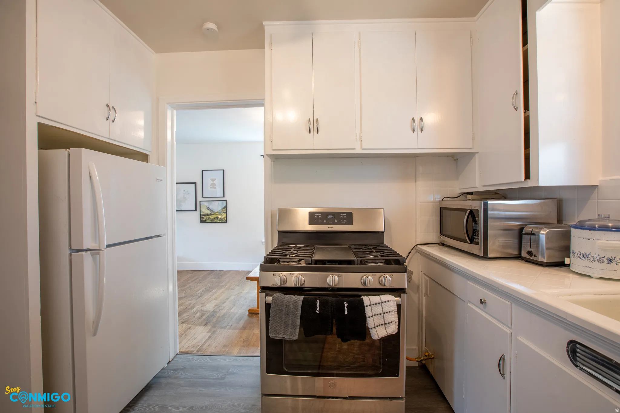 Kitchen featuring stainless steel appliances, white cabinets, and dark wood-style floors