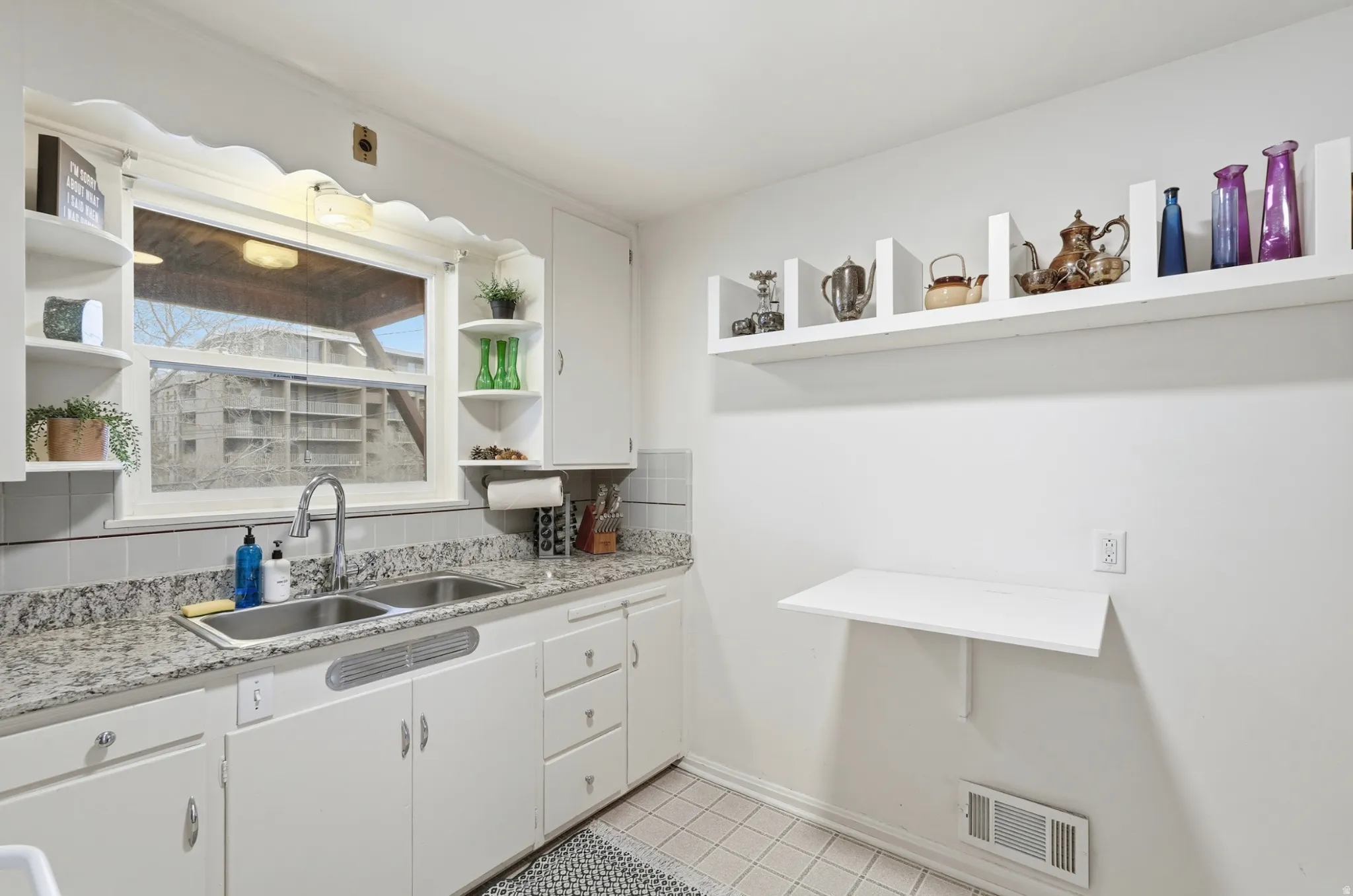 Kitchen with white cabinets, open shelves, light stone countertops, and light tile patterned floors