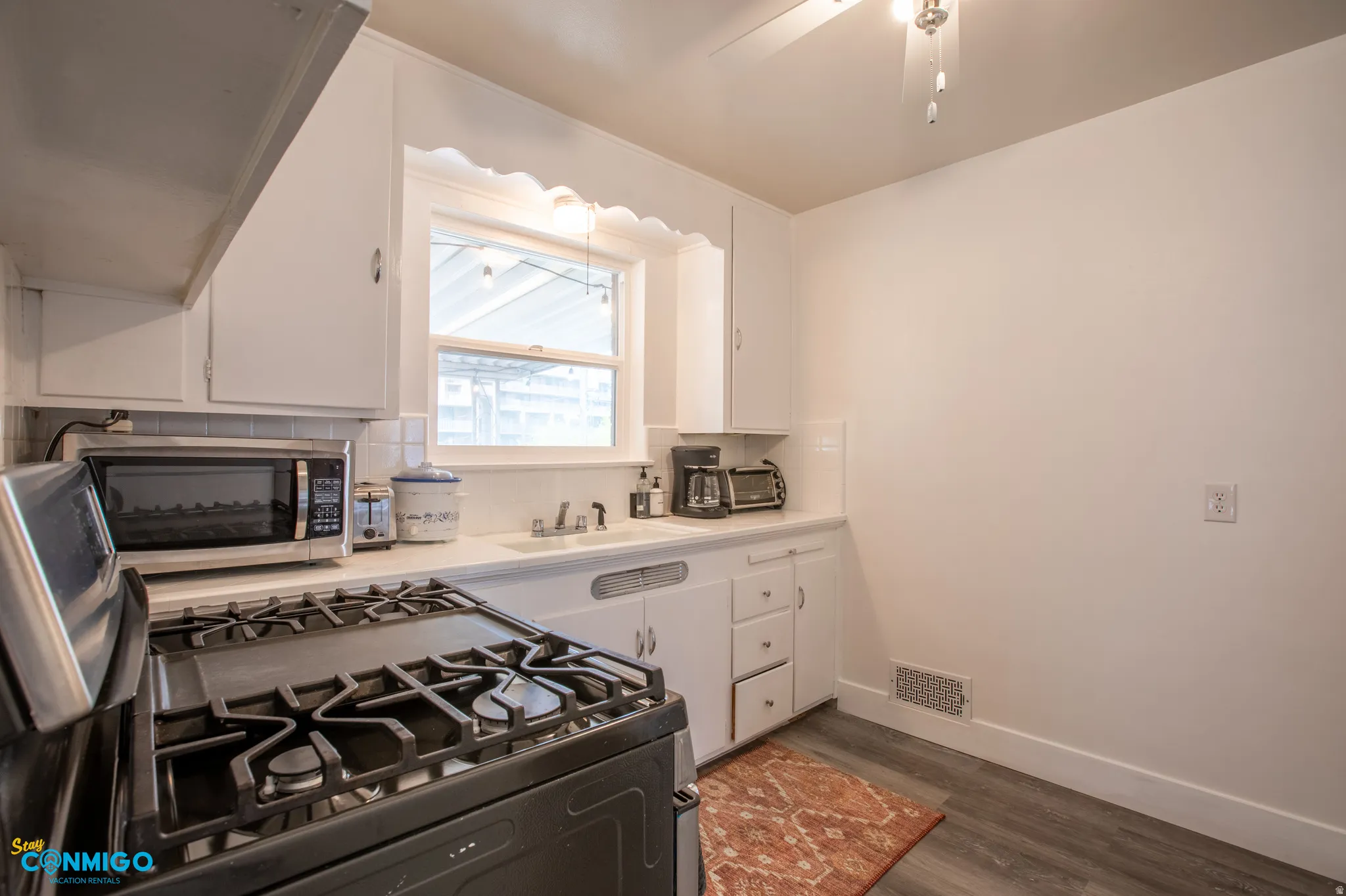 Kitchen featuring white cabinets, light countertops, decorative backsplash, and dark wood-type flooring