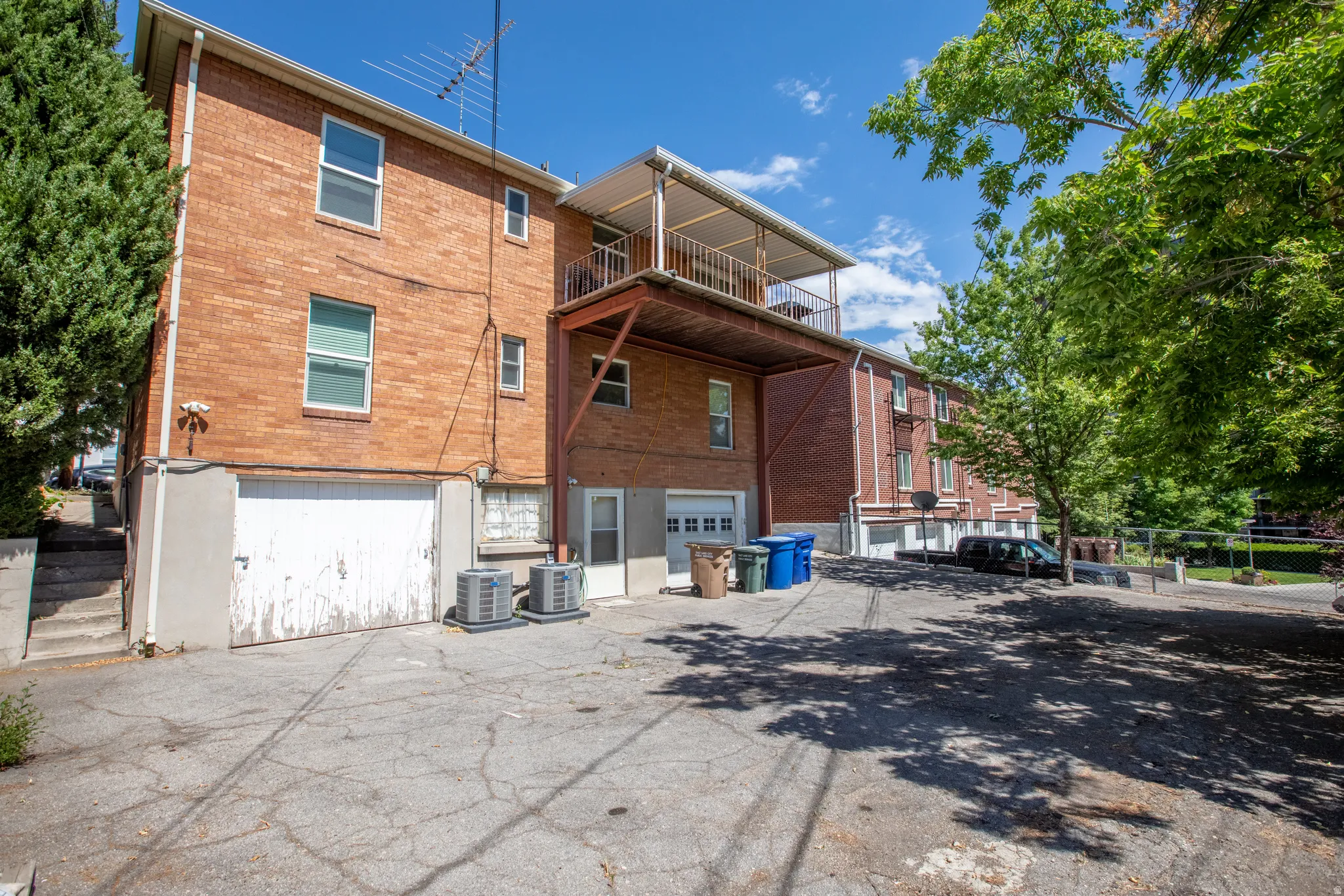 Rear view of house with a balcony, a garage, brick siding, and driveway