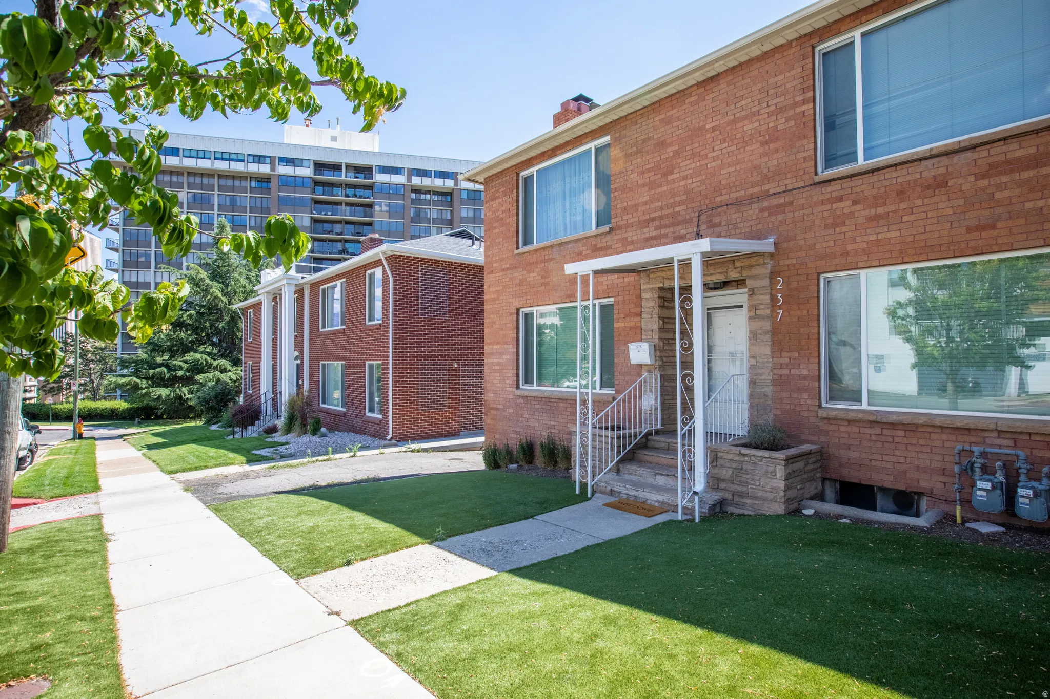 View of front of home featuring a front yard, brick siding, and a chimney