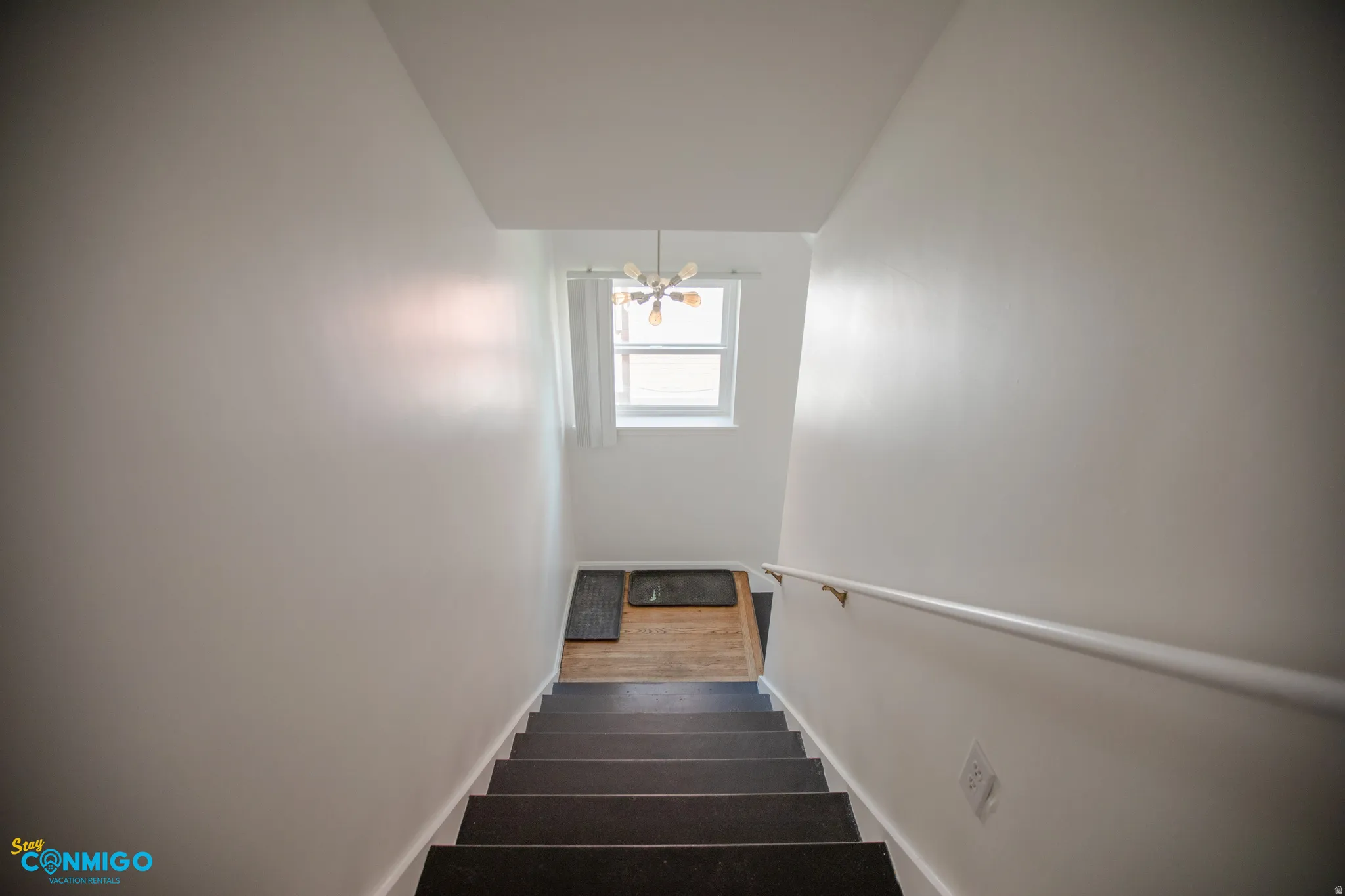 Staircase with hanging lights and baseboards