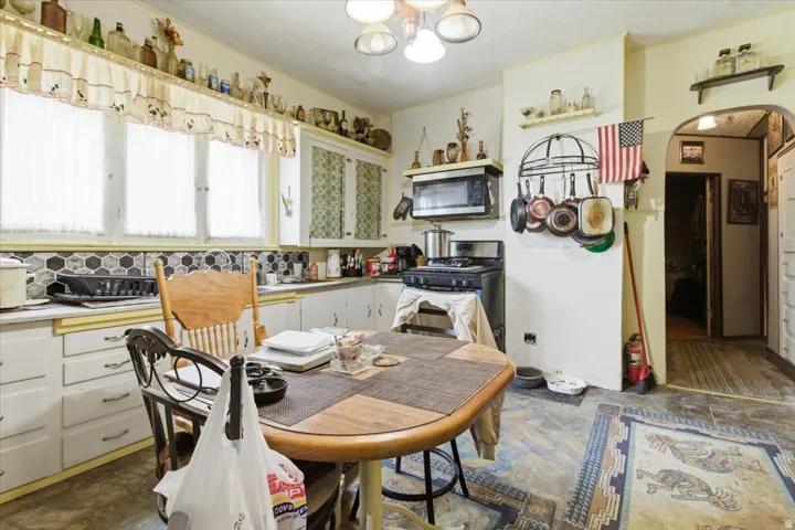 Kitchen with light countertops, stainless steel appliances, white cabinetry, arched walkways, and suspended lighting