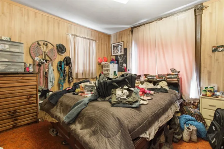 Carpeted bedroom featuring wood walls