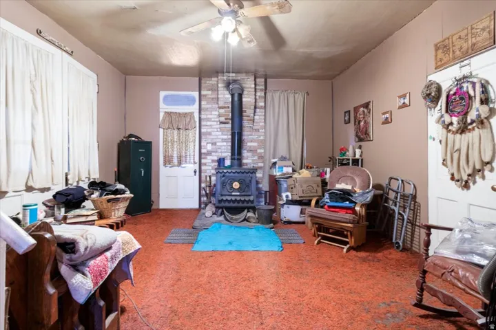 Sitting room featuring a ceiling fan, carpet floors, and a wood stove