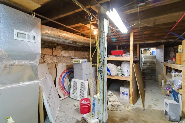 Unfinished basement with heating unit and stairs