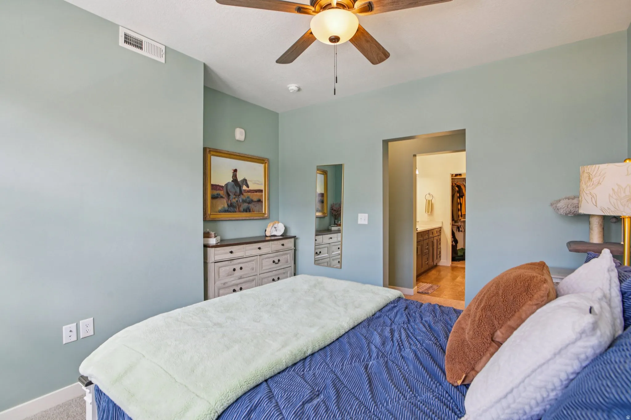 Bedroom with ceiling fan, light carpet, and ensuite bathroom