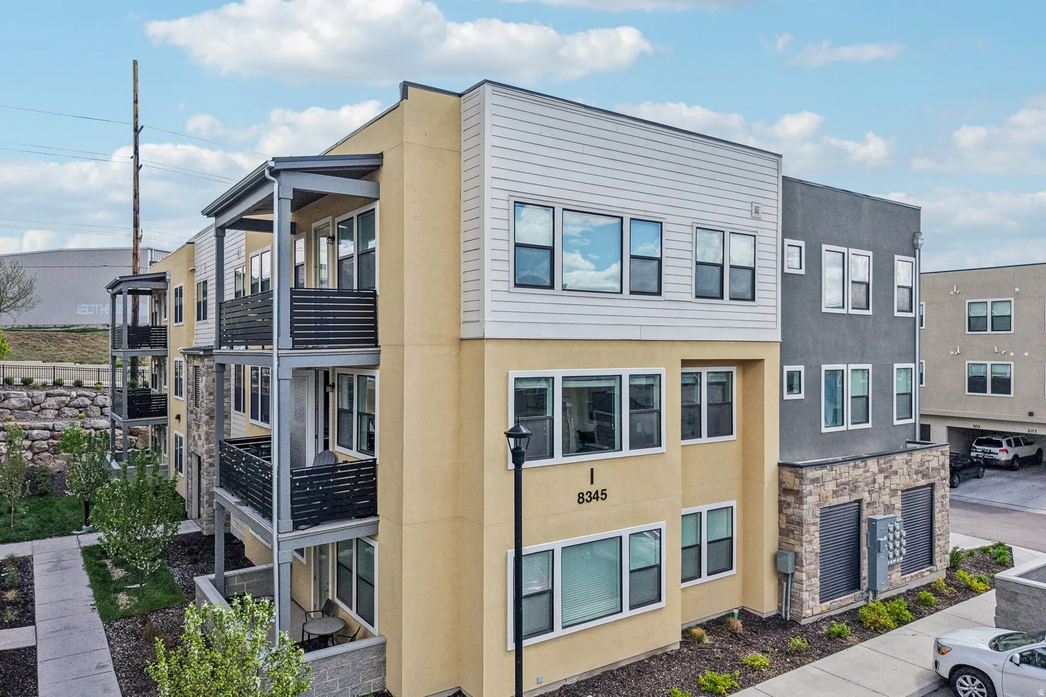 View of home's exterior featuring stucco siding, stone siding, and a balcony