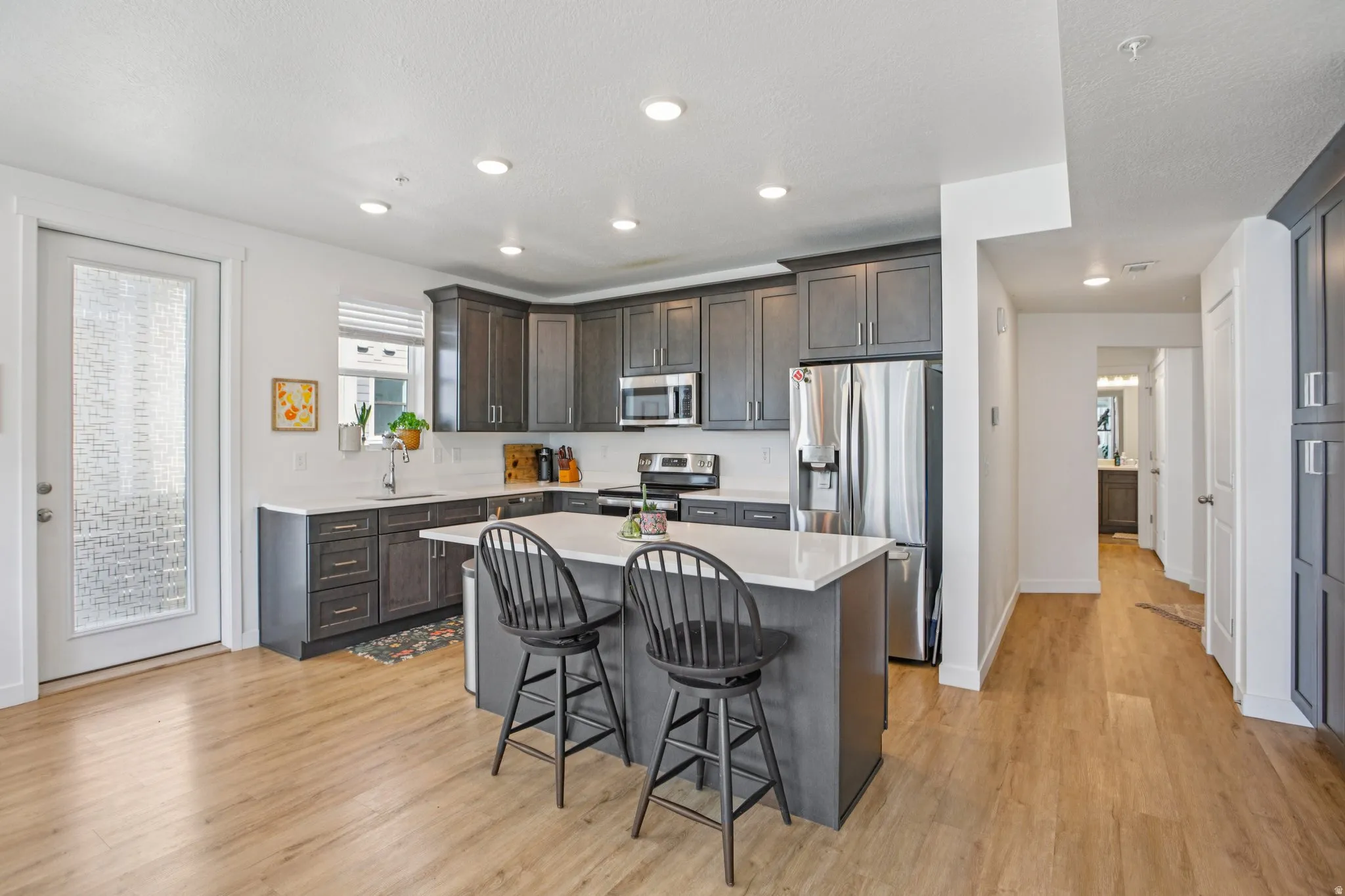 Kitchen featuring stainless steel appliances, a breakfast bar area, a center island, dark wood finish cabinetry, and light wood-style flooring