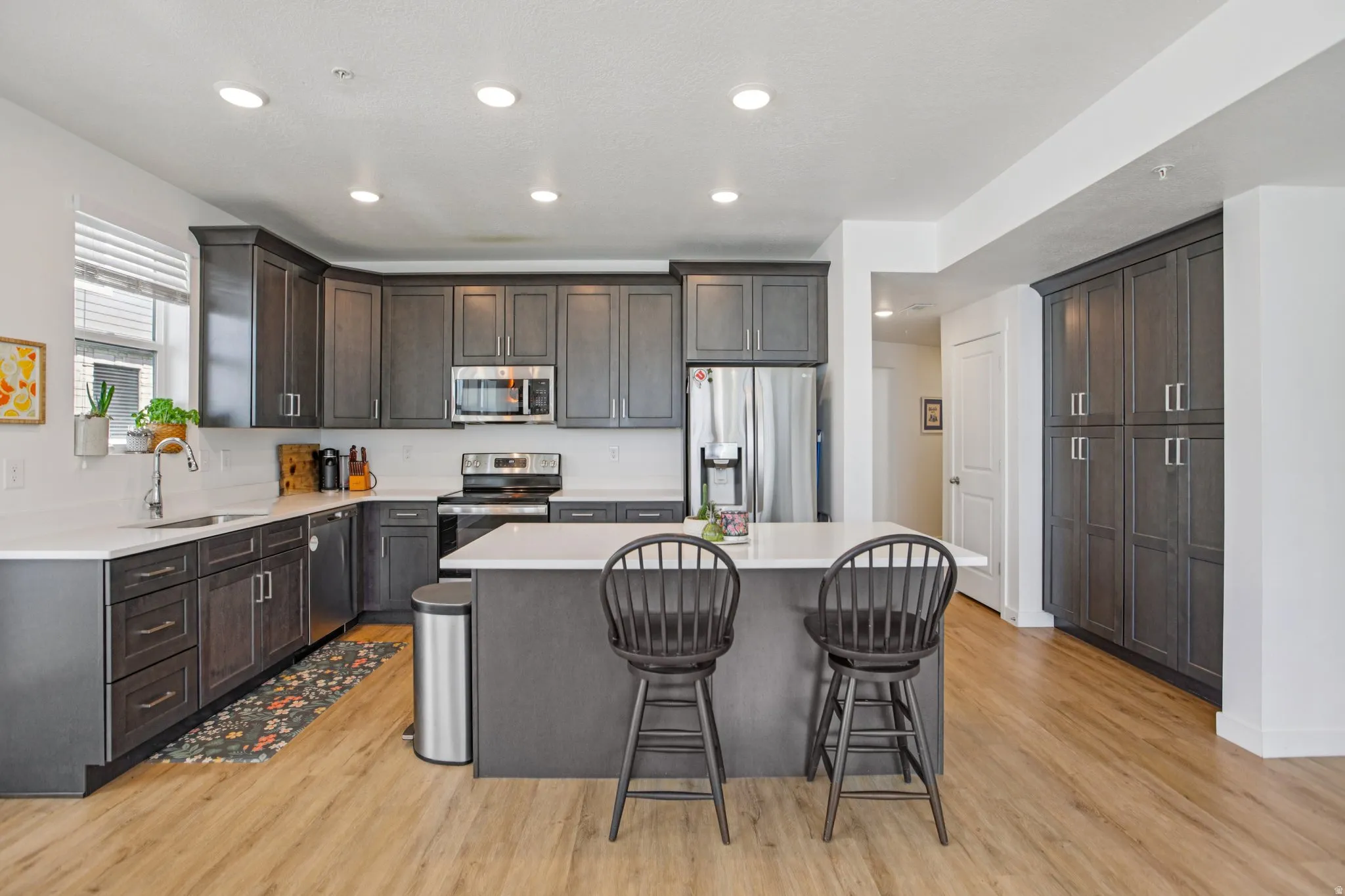 Kitchen featuring stainless steel appliances, a center island, a breakfast bar, dark wood finish cabinets, and light wood-type flooring