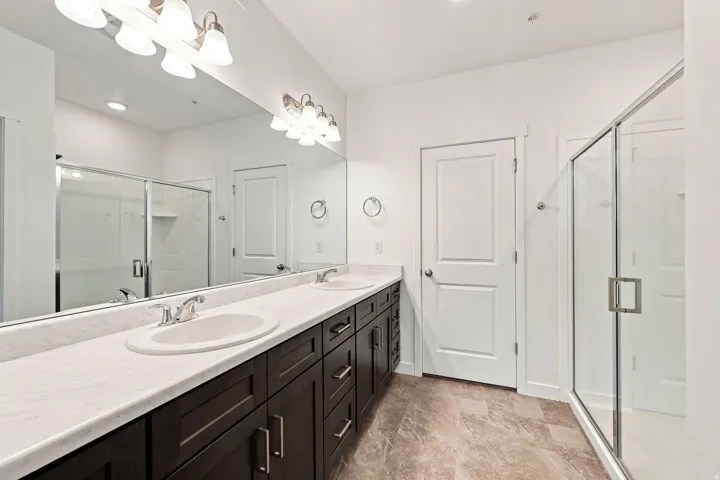 Dual vanity with dark wood-finish cabinetry, white countertop, and integrated sinks