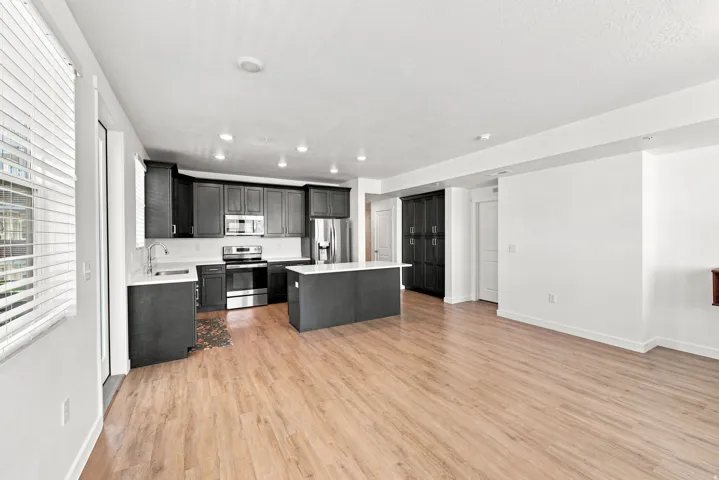 Open-concept kitchen with dark cabinetry, stainless steel appliances, and a central island