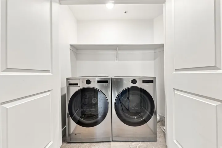 Laundry closet featuring stainless steel front-load washer and dryer, an overhead shelf, and recessed lighting