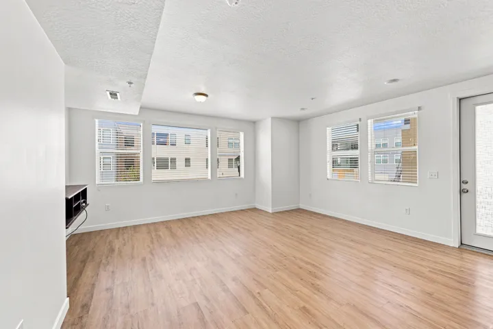Open concept living area with wood-finish flooring, multiple windows, and a white interior paint scheme