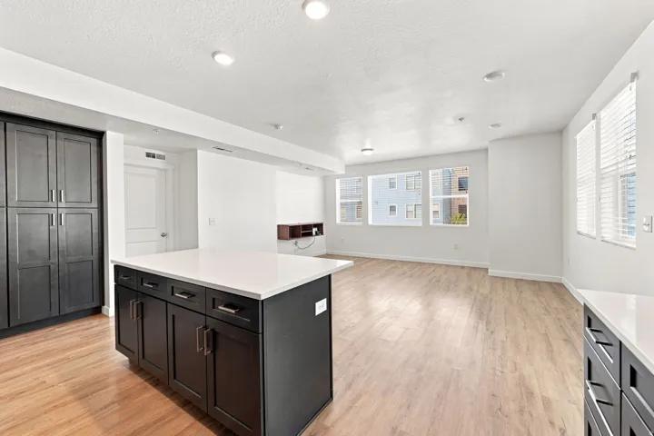 Open-concept living space featuring wood-finish flooring, recessed lighting, white walls, and multiple windows with blinds