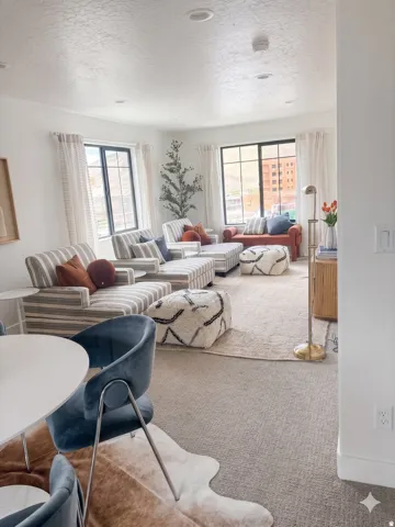 Spacious living area featuring large windows, recessed lighting, white walls, and light-toned carpeting