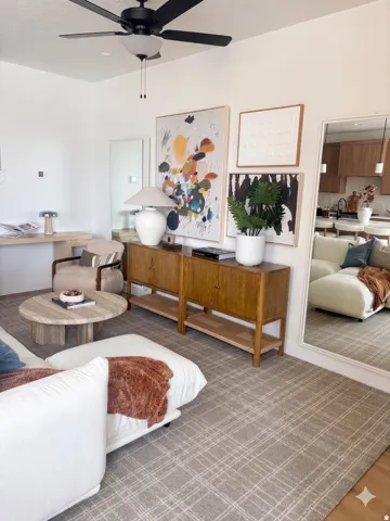 Living area featuring a black ceiling fan with integrated lighting, two wood-finish cabinets with open shelving, and a round stone-finish coffee table