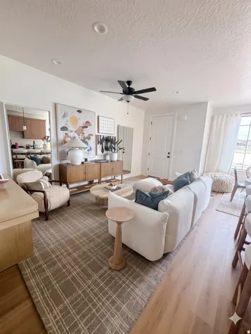 Open-concept living area featuring light wood-finish flooring, recessed lighting, a ceiling fan, and a neutral color palette