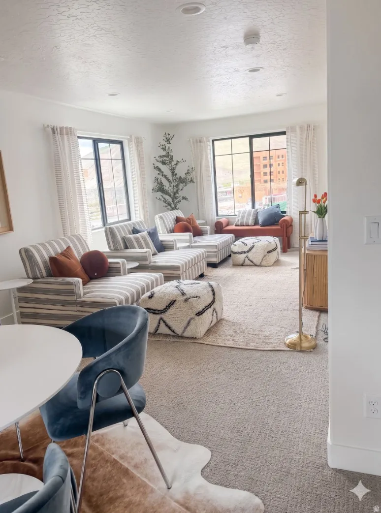 Spacious living area featuring abundant natural light from multiple windows, recessed ceiling lighting, and a neutral carpeted floor