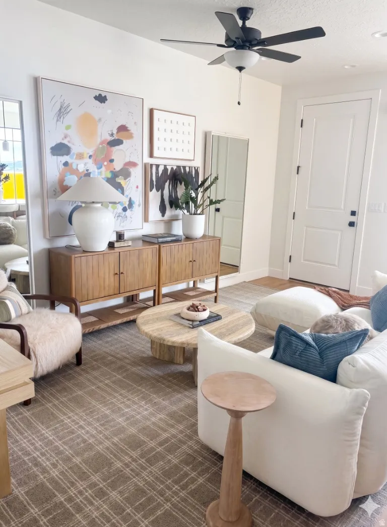 Spacious room featuring a neutral color palette, ceiling fan with integrated lighting, and a paneled interior door with dark hardware