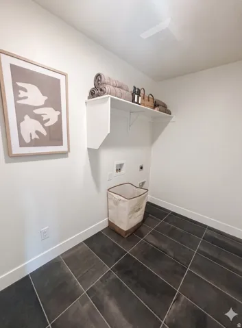 Utility space featuring dark rectangular floor tiles and white wall paint