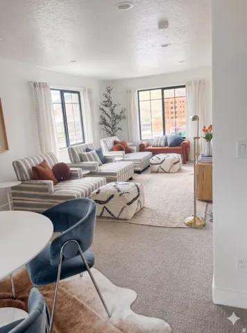 Spacious living area featuring abundant natural light from multiple windows, recessed ceiling lighting, and a neutral carpeted floor
