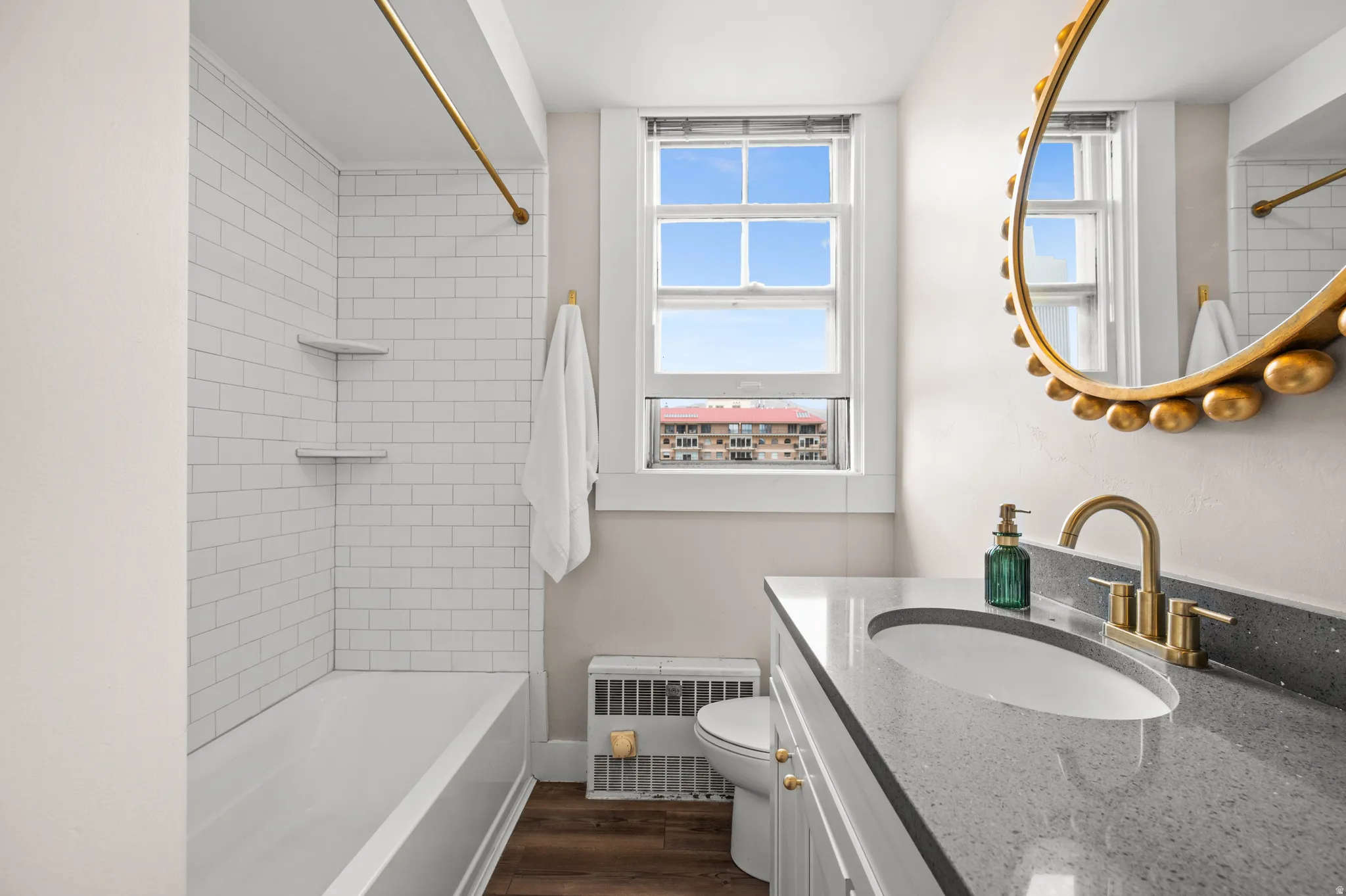 Bathroom with vanity, radiator, dark wood-style flooring, and bathing tub / shower combination