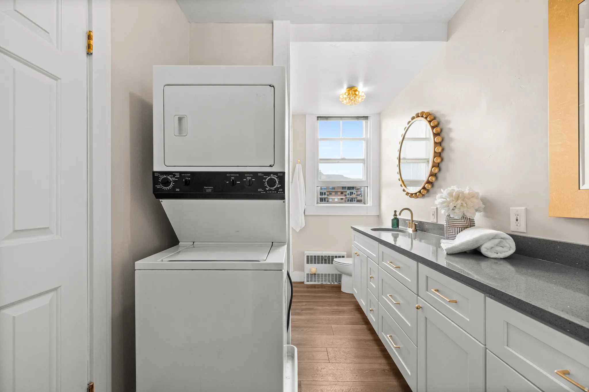 Laundry area featuring dark wood-style floors and stacked washer / dryer
