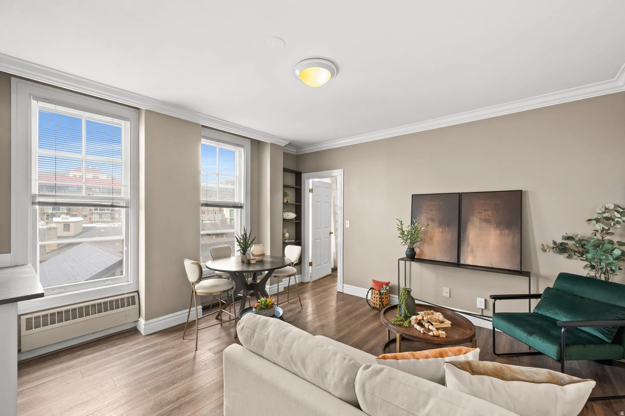 Living room with radiator, wood finished floors, and crown molding