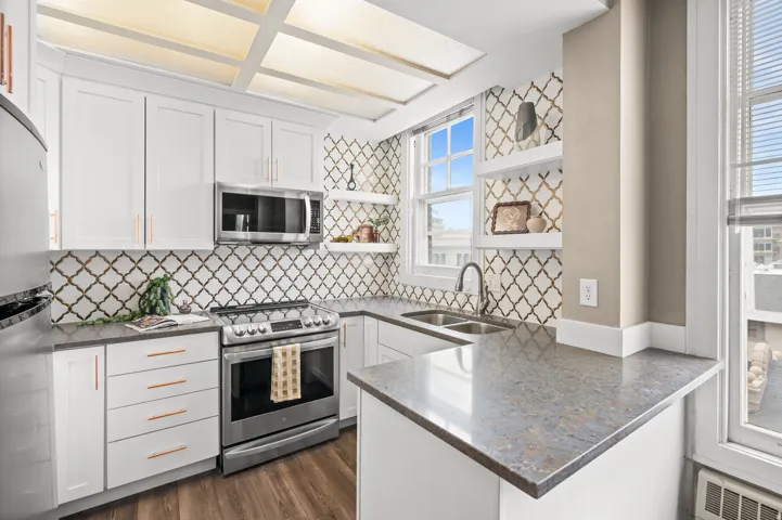 Kitchen featuring a peninsula, open shelves, dark stone counters, stainless steel appliances, and white cabinets