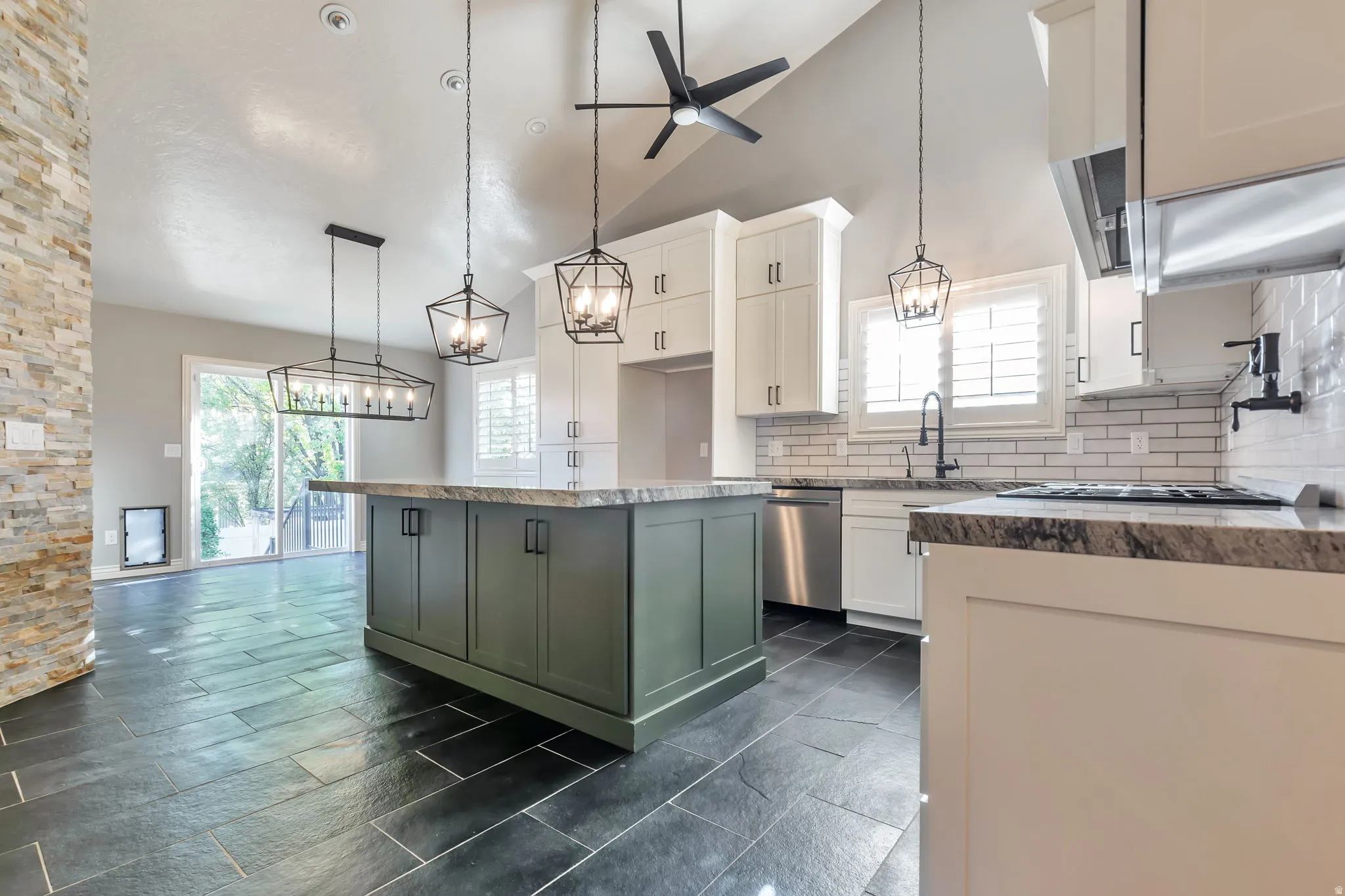 Two tone kitchen featuring two tone color scheme, backsplash, a center island, suspended lighting, and a ceiling fan