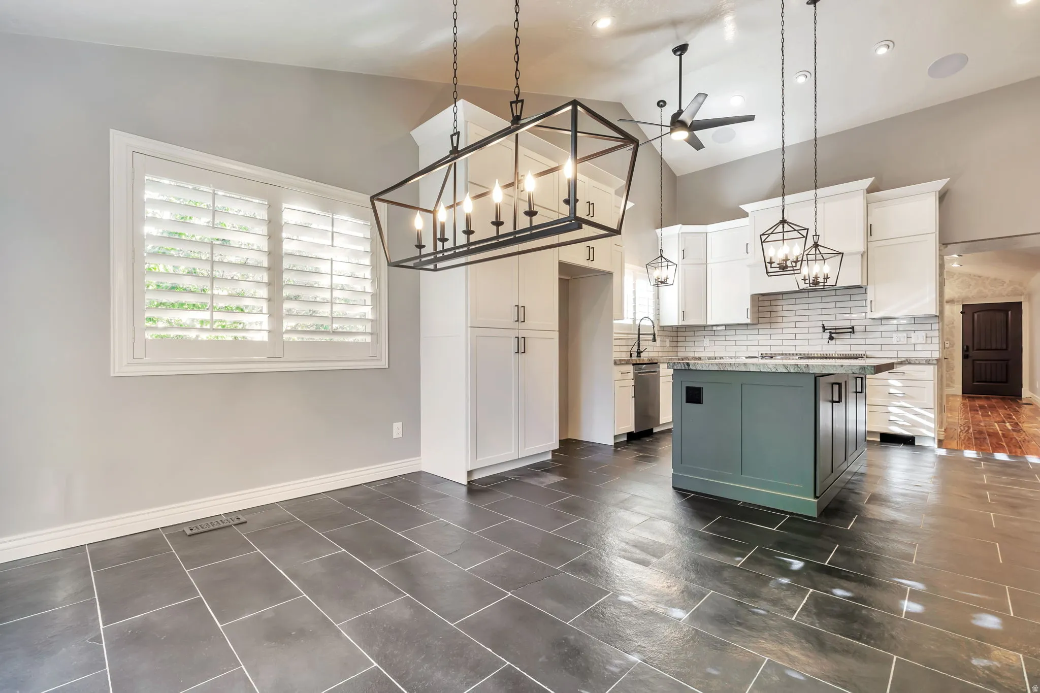 Kitchen with dual tone cabinetry, hanging lights, ceiling fan, a center island, and backsplash