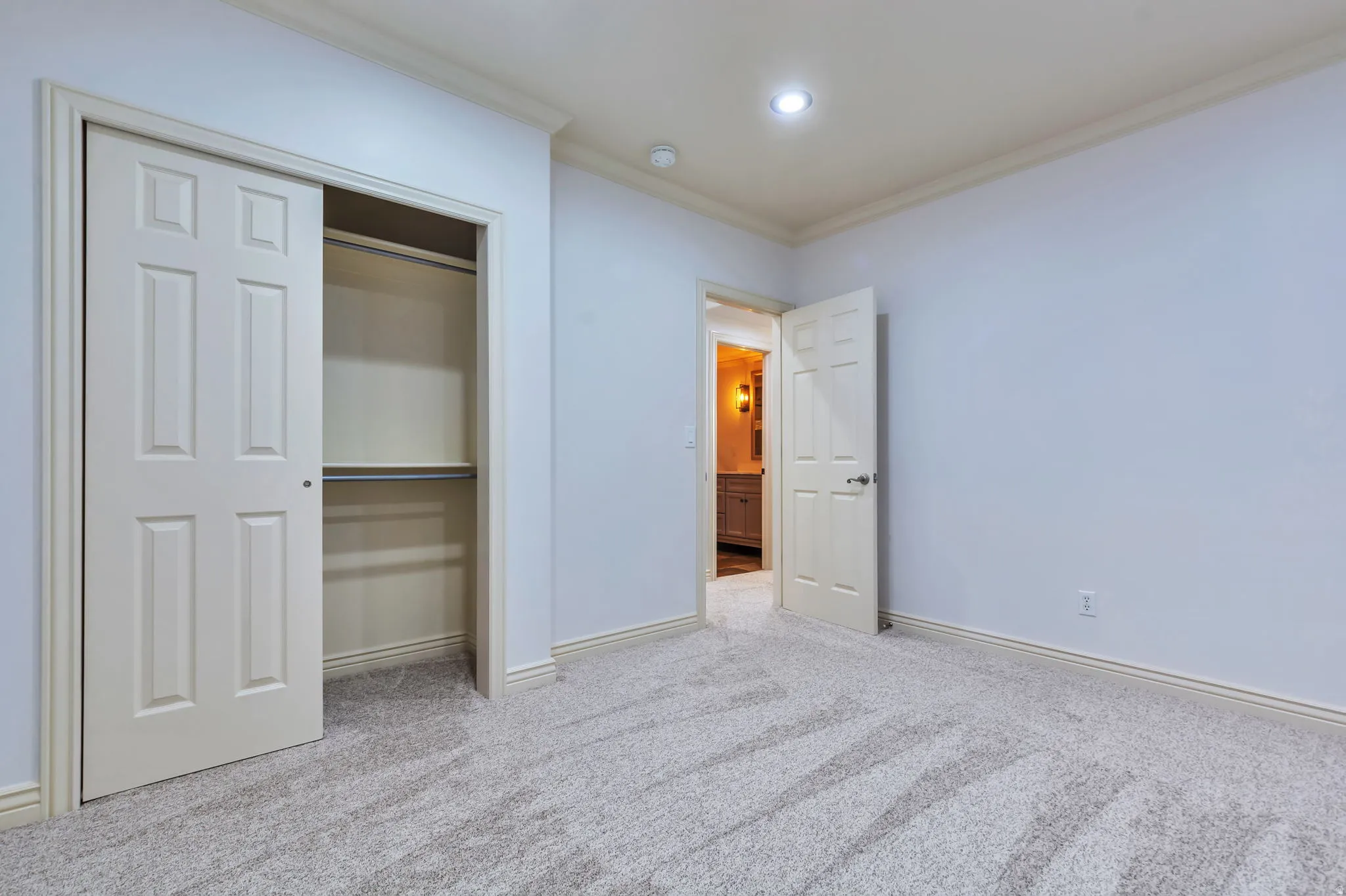 Unfurnished bedroom featuring crown molding, light colored carpet, and a closet