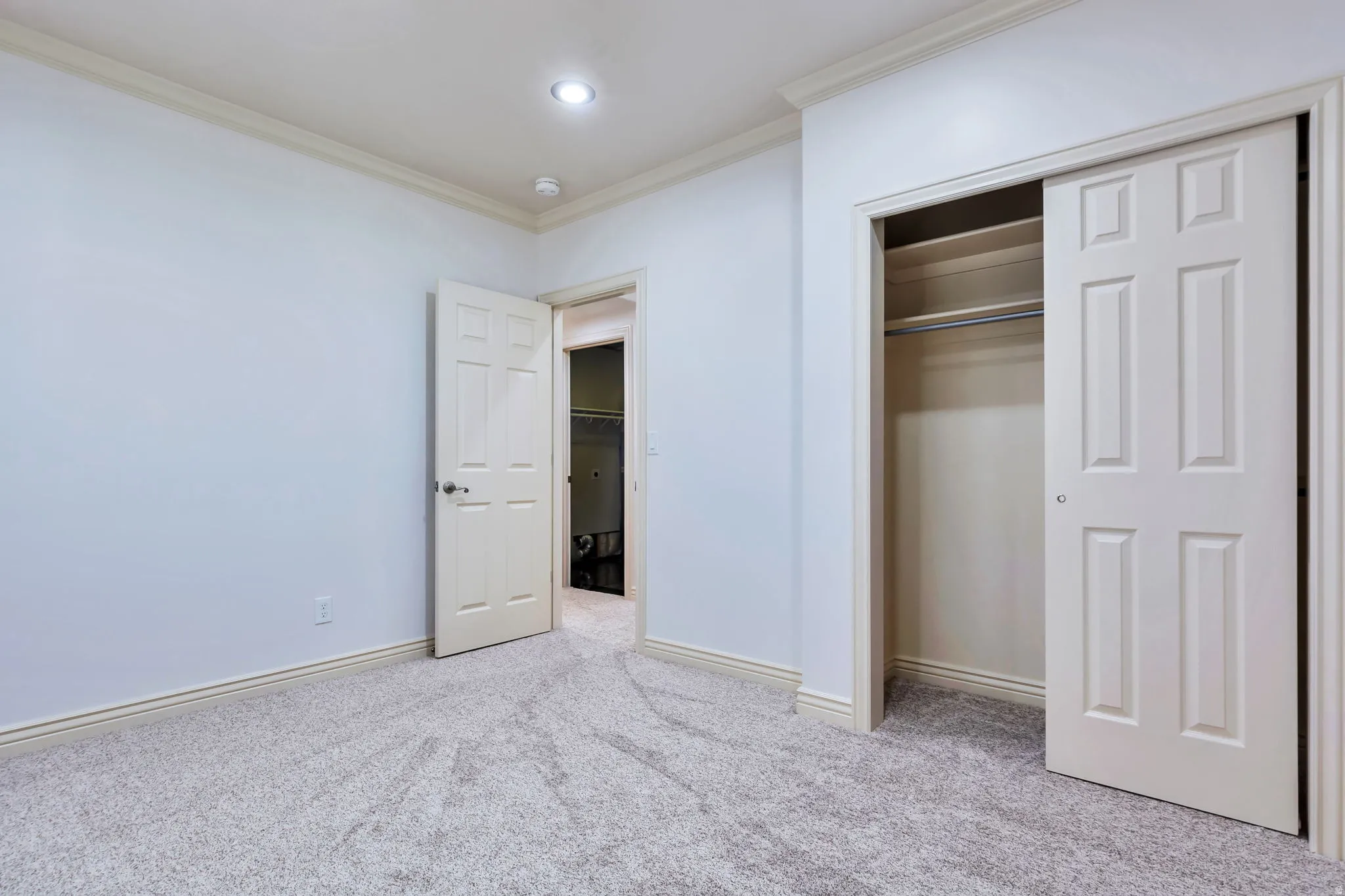 Unfurnished bedroom with ornamental molding, light carpet, and a closet