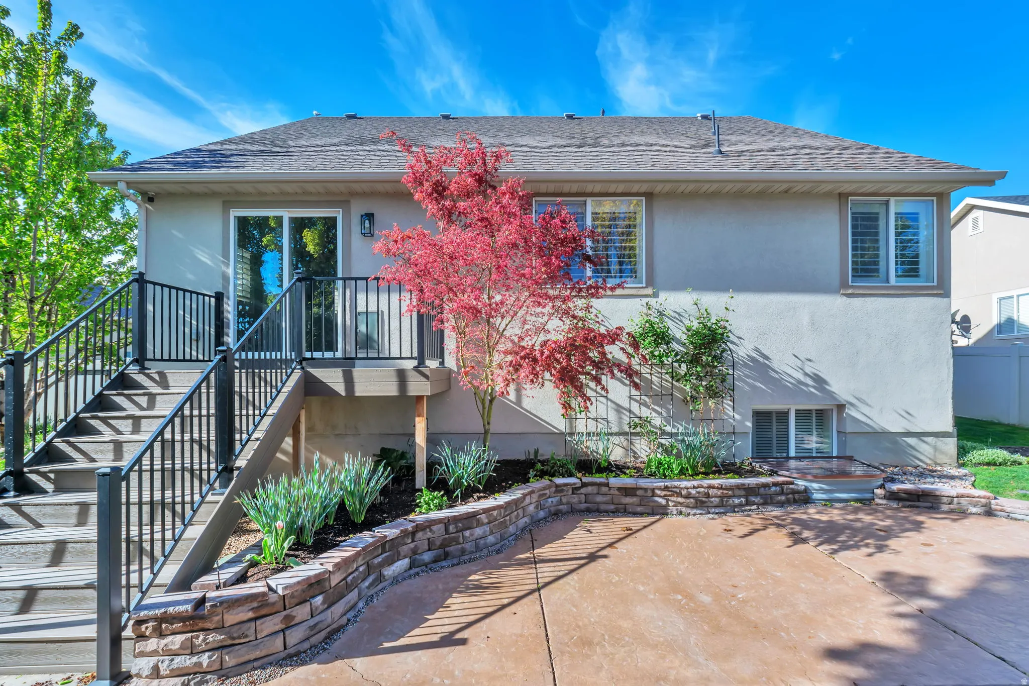 Rear view of property with stucco siding, roof with shingles, and a patio